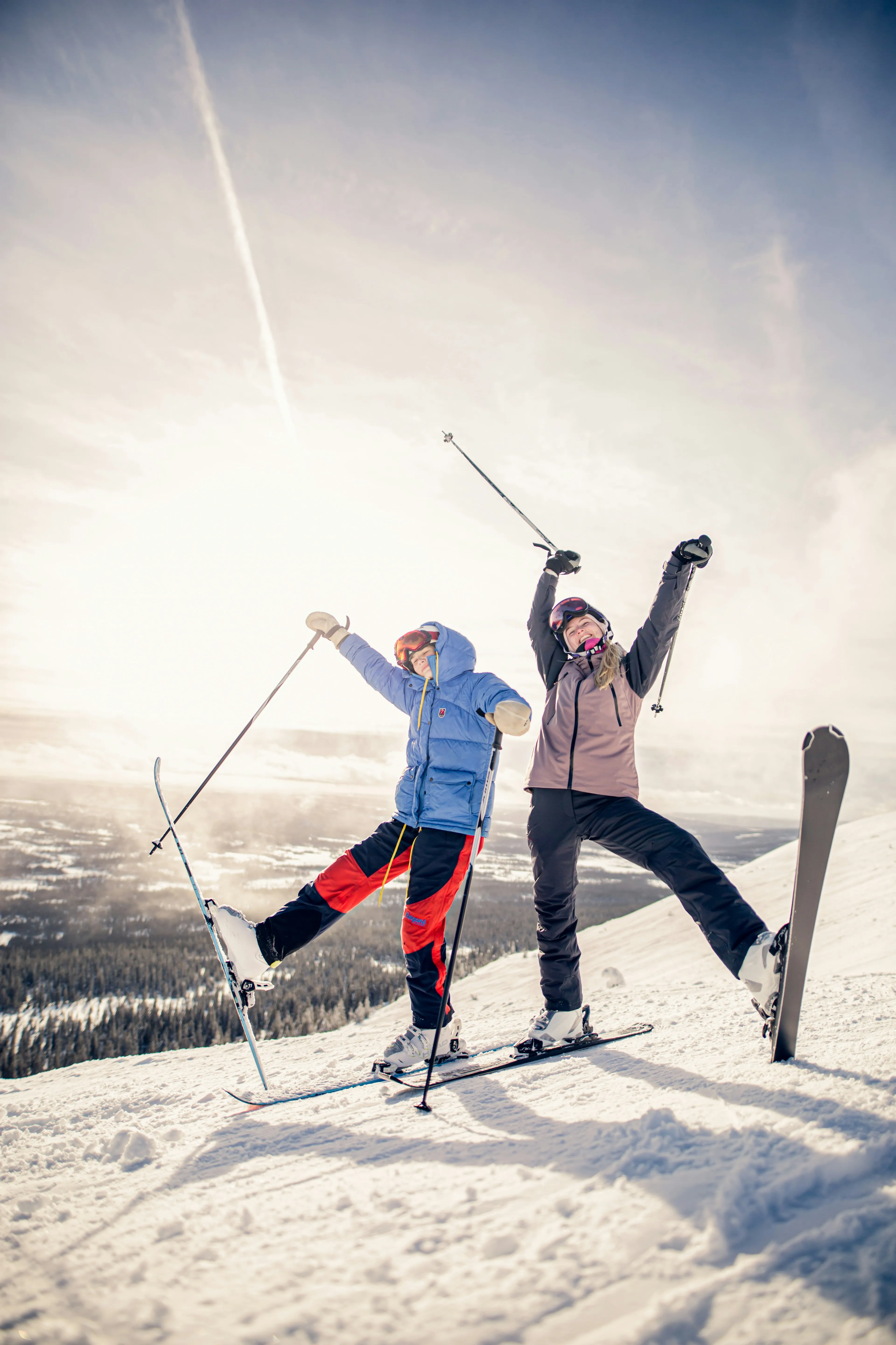 Zwei jubelnde Skifahrer:innen auf dem Gipfel