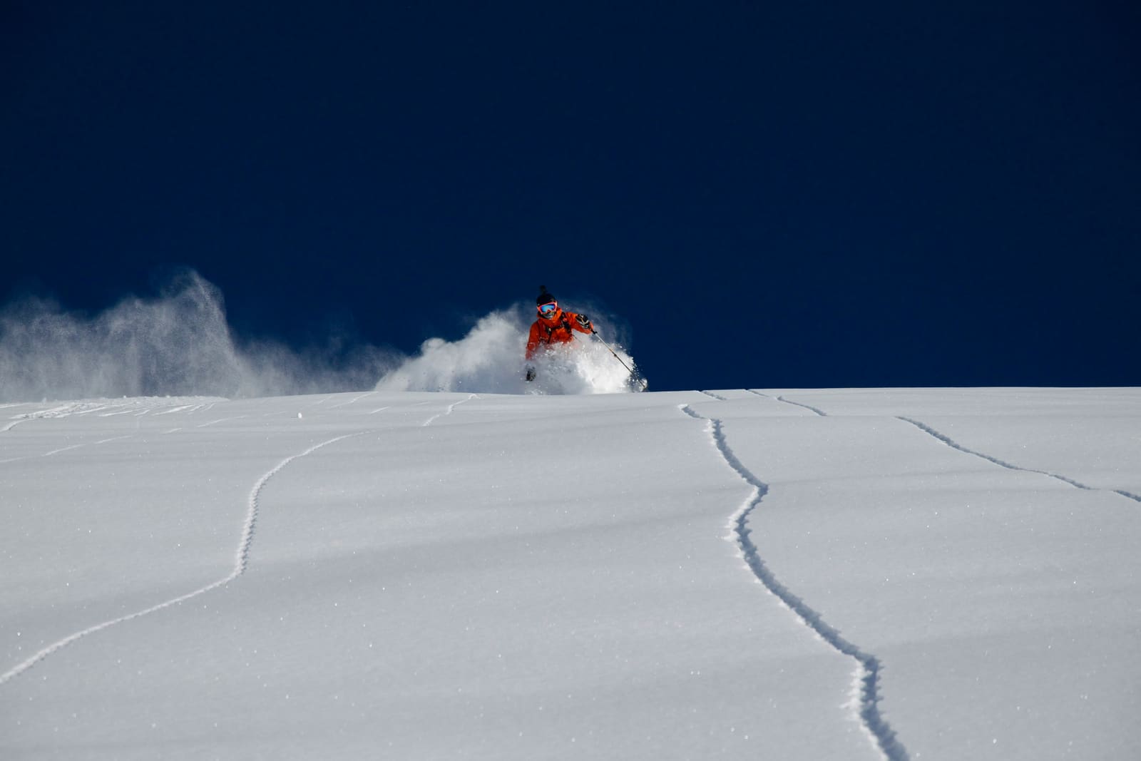 Freerider zieht Spuren in unberührten Pulverschnee unter dunkelblauem Himmel